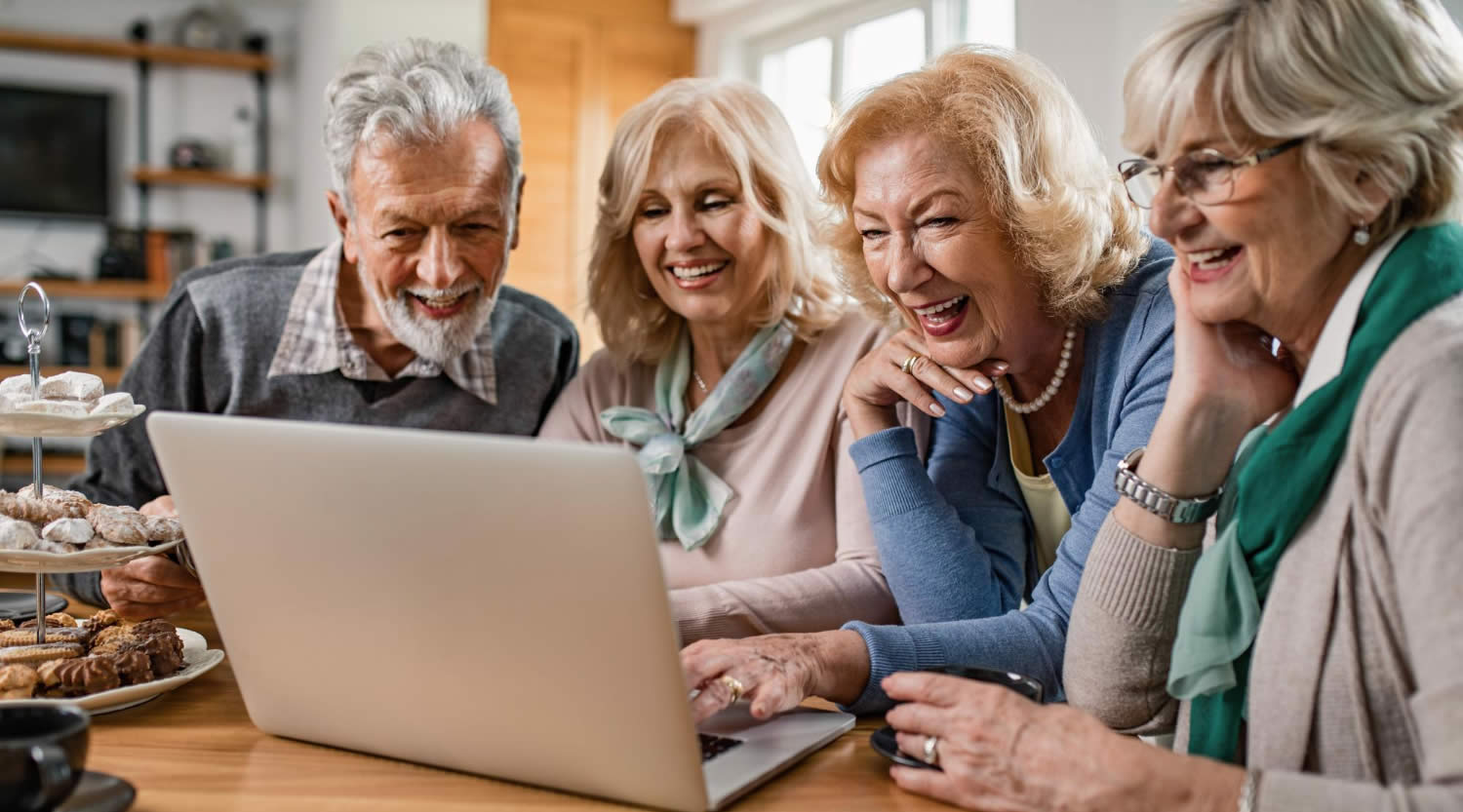 833-happy-senior-friends-enjoying-while-watching-together-something-laptop-home